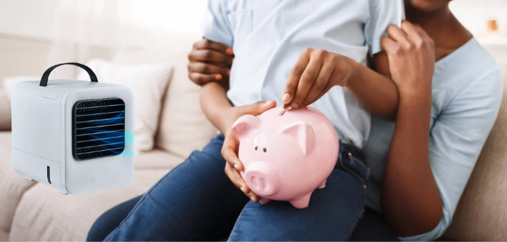 Image of father holding his son on the couch, putting money in a piggy bank. A Chiller Portable AC is next to them